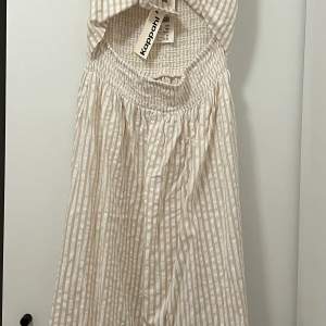 Klänning i bomull från Kappahl. Randigt mönster, knytdetalj fram och smock bak, men klänningen kan användas åt båda håll. 