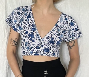 Blommig crop topp med bar rygg - Blå, vit blommig crop topp med bar rygg där man knyter baksidan själv. Väldigt fin men inte min stil längre