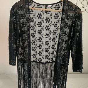 kimono med fransar - Svart kimono med fransar från H&M som ger en avslappnad boho-stil. I bra skick, bara använd ett fåtal gånger. Har ett fint blommigt mönster! Pris kan diskuteras. 🪷