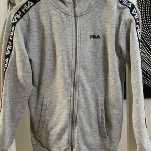 Fila zip hoodie  - en snygg zip hoodie från Fila i storlek 146-152. En blå liten tuch rand på bröstet som är typ 1cm men den syns knappt bara om man kollar noga 