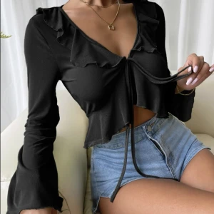 Svart topp - En svart, lite see through topp. Super fin med knyte där fram