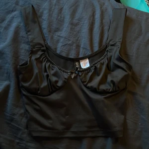 Svart topp - En svart topp med ”kupan” insydd, det har blivit för liten för mig och har används ett fåtal gånger ( nästan som nyskick ) en liten rosett finns även i fram