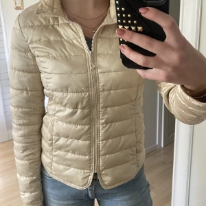 Dunjacka  - Perfekta höstjackan! En beige ganska tunn dunjacka som passar perfekt att ha som den är eller under en jacka