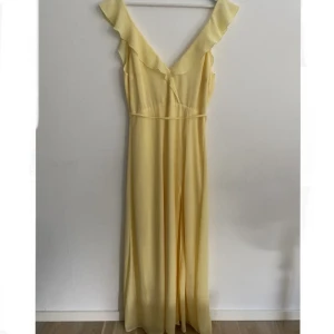 Gul balklänning  - Gul hellång balklänning från Nelly med en slits.