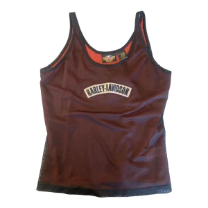 Meshlinne, Harley Davidsson  - Linne med två lager meshtyg. Tyget är lite stretch i. Broderad påsydd Harley-Davidson logga på bröstet.  Linne med två lager meshtyg. Tyget är lite stretch i. Broderad påsydd Harley-Davidson logga på bröstet. Mått: Längd:45,5cm Bredd: 42cm