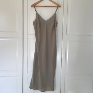 Siden liknande klänning - Superfin sidenliknande klänning i beige skimrande färg⭐️Går till mitten av vaderna på mig, med en slit på baksidan (kan skicka bild)💗inga fläckar men lite nopprig