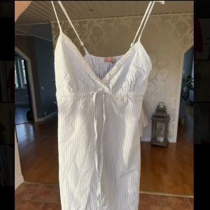 Sommarklänning  - Supersöt sommarklänning i vit/blå randigt tyg. Justerbara axelband och ett snöre du kan dra åt under brösten. En sommardröm!🥰  Skriv om du vill ha fler bilder🫶🏼