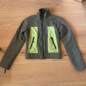 Grön vårjacka - Limegrön/khaki grön jacka i strl S men sitter som en XS. Lätt vadderad, passar våren och sommarkvällar.   