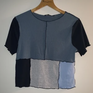 Oanvänd t-shirt - Blå/grå t-shirt med lappad design. Helt oanvänd med prislappen kvar!! Storlek L men passar allt ifrån XS-L