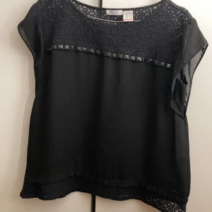 Svart blus - Fin blus med typ nitar och spetsdetaljer, superskönt material! Vet inte riktigt storleken men skulle bedöma den till typ 38, säljer då den är för stor för mig