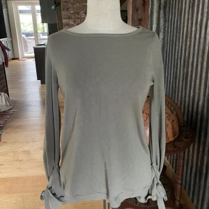 Långarmad tröja från Vila -  Grön långarmad tröja med fin snörning i armarna.