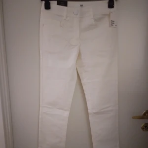NYA oanvända vita snygga smala byxor. Storlek: 34. Liten defekt. - Smala snygga vita byxor med raka ben. Har fickor fram och bak. Hällor för bälte/skärp. Storlek: 34/ XS-SMALL. Material: Bomull. Helt nya och oanvända. Har dock en liten ljusbrun-aktig fläck på ena benet baktill men går troligen enkelt bort vid tvätt.