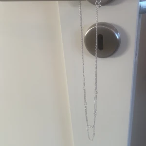 Halsband - Jag säljer detta halsband pågrund av att jag själv valt att satsa på guld smycken. Halsbandet är silvrigt med små vita pärlor. Hakbandet är köpt för 200-300 kr.