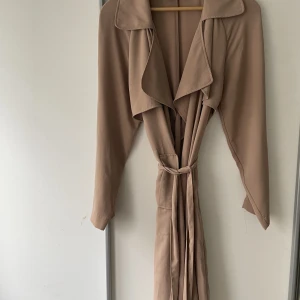 Trenchcoat Bikbok - Sparsamt använd kappa från bikbok. Storlek L, passar mig som har S. Tunnt material, bra för vår/sommar.