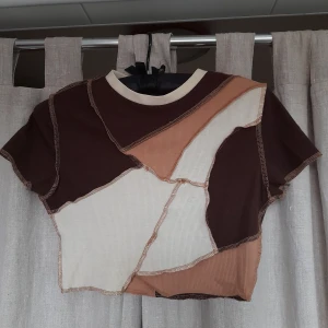 Inverted topp - Mönstrad magrtöja i brun/vitt. Tröjan är i stretchingt ribbat material. Kan bäsas både enligt första bilden där sömmarna är utåt och inåttvänd enligt sista bilden med sömmarna innåt. Lapparna är bortklippta med upskattar storlelken till s eller mindre.