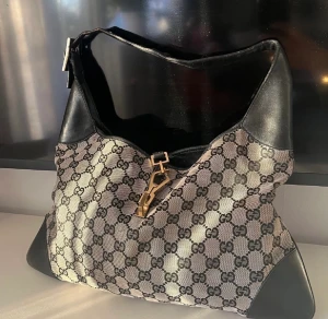 Gucci väska - Säljer min Gucci väska i modellen Jackie canvas gg pattern. Det är mellan modellen. 23x35x1 cm. Handtaget är 36 cm. Den är i fint skick men använd.