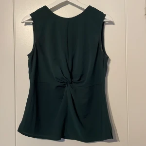 Kortärmad blus - En kortärmad blus med knytdetalj i mörk oliv