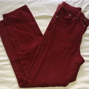 Röda jeans - Jeans som aldrig är använda och ser vintage ut. Insydda i midjan och stängs med fyra knappar. Midjemått ca 63cm. Innerbenslängd ca 70cm. Vikt ca 500g.