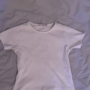 Basic vit t-shirt - En söt liten vit t-shirt🤍 Säljer för att jag inte tycker om den så mycket mer. PS. De är inte en tight t-shirt, den är lös längre ner på tröjan