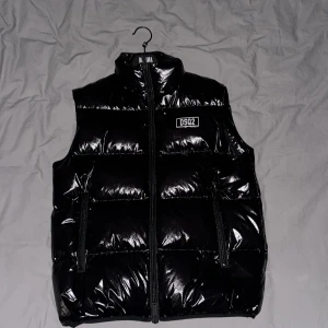 Dsquared2 SVART VADDERAD OCH QUILTAD VÄST FÖR MÄN - Svart glansig Dsquared2 väst, storlek 54 
