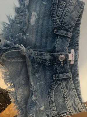 Blå jeansshorts från Gina Tricot - Säljer ett par  blå lowwasit jeansshorts från Gina Tricot i storlek XXS. Shortsen har fransiga kanter, slit detaljer och fem fickor:) Inga defekter, använda en gång och därefter borttappad i garderoben och nu är det dags för utrensning! Priset får alltid att diskutera!❤️☺️