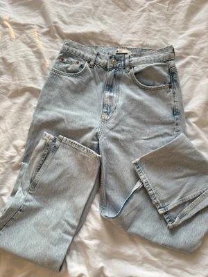 Ljusblå raka jeans med hög midja - Säljer ett par ljusblå jeans med rak passform och medel hög midja. Klassisk femficksmodell med knappgylf och bälteshällor. Jeansen har en tidlös look och är perfekta till alla typer av outfits.