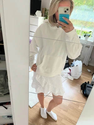 Vit omlottkjol med volang - Säljer en söt vit kortkjol i omlottmodell med volangkant. Kjolen har en luftig och lätt känsla, perfekt för varmare dagar. Tillverkad i ett mjukt bomullstyg som ger en avslappnad och fräsch look.