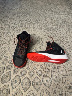 Air Jordan Flywire - Snygga höga sneakers från Jordan i svart med röda detaljer och vit mellansula. Skorna har röda och svarta skosnören, samt en röd yttersula. Ikonisk Jumpman-logga på sidan och vadderad plös för extra komfort. Air Jordan Flywire, ganska bra skick, storlek 47,5, fraktar samma dag eller dagen efter :) 