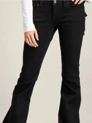Svarta lågmidjade true religion jeans - Snygga svarta bootcut jeans med klassiska fem fickor och knappgylf. Jeansen har en utsvängd passform nedtill och är tillverkade i ett stretchigt denimtyg som sitter bekvämt. Perfekta för dig som gillar en retroinspirerad look.