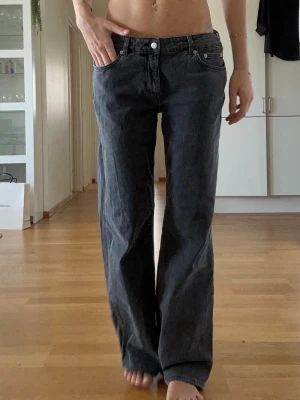 Vida svarta jeans med låg midja - Är 178cm lång! Säljer ett par svarta jeans med låg midja och raka, vida ben. Jeansen har klassisk femficksmodell och silverfärgade knappar. Perfekta för en avslappnad och trendig look. Materialet är denim i bomull.
