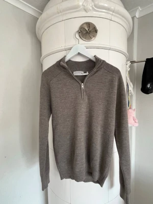 Beige stickad tröja med halv dragkedja - Snygg beige stickad tröja från SANDÖ med halv dragkedja och ribbade muddar. Perfekt för lager på lager och har en stilren, enkel design som passar till det mesta. Materialet känns mjukt och bekvämt, och tröjan har en hög krage. Knappt använd och är i väldigt bra skick. Storlek s. Kolla även mina andra annonser så kan vi lösa paketpris