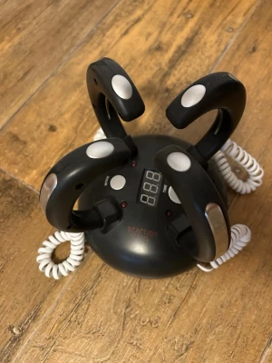 Elektroniskt reaktionsspel - Säljer ett svart elektroniskt reaktionsspel med fyra handtag och digital display. Spelet har vita och silverfärgade knappar samt spiralformade sladdar. Perfekt för att testa reaktionsförmåga tillsammans med vänner. Rund form och tillverkad i plast.