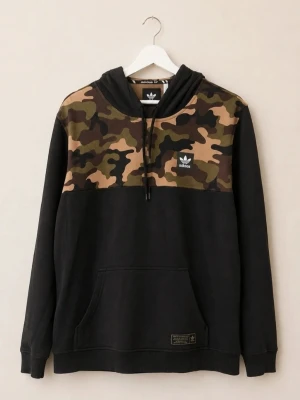 Adidas Originals Hoodie Camomönster Treefoil y2k streetwear  - Snygg svart hoodie från Adidas med camomönstrad panel över bröst och axlar. Klassisk huva med svarta dragsnören och Adidas-logga på bröstet. Känguruficka framtill och tre svarta ränder på huvan. Perfekt för en streetwear-look.