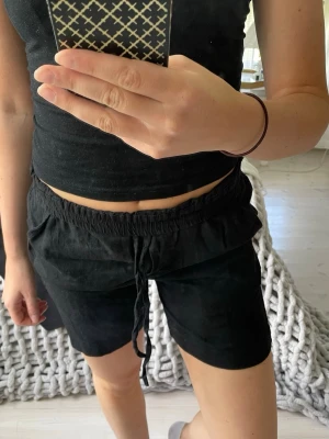 Svarta linneshorts - Svarta linneshorts med elastisk midja och snörning framtill. De har en avslappnad passform och är perfekta för varma dagar. Knappt använda. 