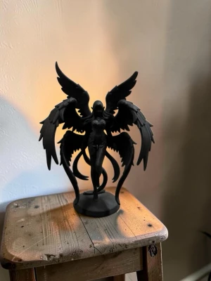 Svart ängelstaty med vingar - Unik svart staty föreställande en änglalik figur med stora, detaljerade vingar och huva. Figuren står på en rund bas och har en mystisk, fantasy-inspirerad design. Perfekt som dekoration för dig som gillar fantasy eller vill ha något coolt till rummet.
