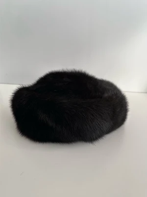 Svart pälsbasker / mössa i 100% äkta minkpäls - Eleganta och stilren svart pälsmössa / mössa / hatt i 100& äkta mink i storlek M / 57 (inre omkrets 57 cm), Klassisk design med rundad topp och bred mjuk kant runtom. Fodrad i matchande svart färg. En stilfull, kvalitativt sydd tidlöss klassiker som kommer förhöja alla kalla dagar. Mycket gott skick, som ny!