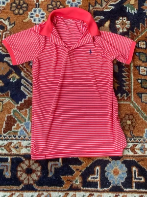 Polo Ralph Lauren - Äkta Polo Ralph Lauren tröja nästan aldrig använd, där de finns nästan inga tecken på användning. Den har röda och vita ränder med en klassisk krage. Storlek är M i BARNSTORLEK! Matrial är Polyester. Skriv om frågor och prisrekommendationer!😊
