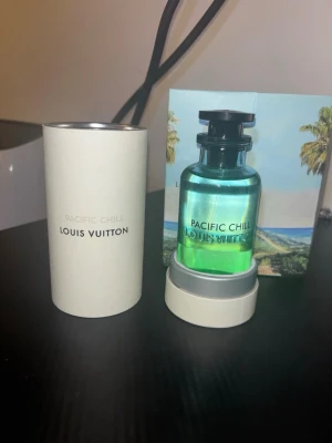 Louis Vuitton Pacific Chill parfym - Fräsch parfym från Louis Vuitton, Pacific Chill. Flaskan är genomskinlig med grönblå vätska och svart lock. Kommer i elegant vit cylinderförpackning och medföljer en kartong med tropiskt motiv. Lyxig och modern design. Har viktig information till dig som är intresserad.