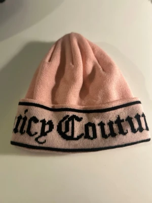 Juicy Couture Flat Knit Beanie - Juicy Couture. Modell: Ingrid Flat knite beanie. Med uppvikt kant och svart logotyp runt om. Tillverkad i mjukt stickat material. Perfekt accessoar för att lyfta din outfit med en trendig touch. Oanvänd. Köpt från Nelly 450kr