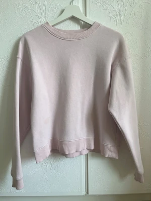 Ljusrosa oversized sweatshirt - En enkel och stilren ljusrosa sweatshirt i oversized modell. Tröjan har rund halsringning, långa ärmar och ribbade muddar vid ärmslut och nederkant. Tillverkad i mjukt bomullsmaterial som känns skönt mot huden. Perfekt för en avslappnad och trendig look. Har dock en liten oljefläck