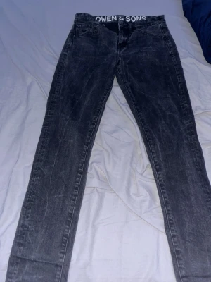 Size w28 L32 Svarta  jeans Owen & Sons - Säljer ett par svarta tvättade jeans från Owen & Sons med klassisk femficksmodell och raka ben. Jeansen har en snygg sliten look och tydliga sömmar. Perfekta för dig som gillar en avslappnad och trendig stil.