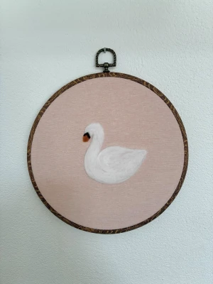 Tovad tavla med svan - Rund tavla med tovad svan och ljusrosa bakgrund i tyg. 22cm i diameter. Perfekt för barnrummet 🦢