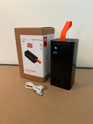 Powerbank 80000mAh med display - Stor svart powerbank med kapacitet på 80000mAh, digital display och orange bärrem. Levereras med USB-laddkabel och originalkartong. Perfekt för att ladda mobilen eller surfplattan när du är på språng. Rektangulär form och modern design.