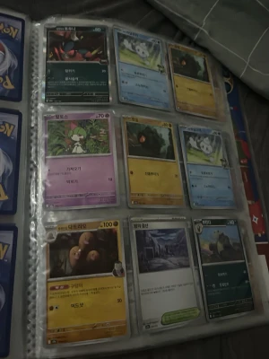 Pokémonkort i samlarpärm - Säljer ett ark med Pokémonkort i en samlarpärm. Korten har olika färger och motiv, bland annat gräs-, vatten-, el- och psykiska Pokémon. Texten på korten är på koreanska och de ligger i plastfickor. Perfekt för dig som gillar att samla Pokémonkort.