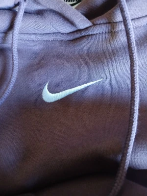 Brun hoodie från Nike med logga - Säljer en brun hoodie från Nike med klassisk vit swoosh-logga broderad på bröstet. Hoodien har huva med dragsko och en stor magficka framtill. Tillverkad i mjukt bomullsmaterial, perfekt för en avslappnad och sportig stil.