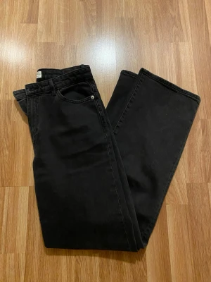 Svarta wide leg jeans med stretch - Säljer ett par svarta wide leg jeans med hög midja och lätt stretch. Jeansen har klassisk femficksmodell och raka, vida ben. Perfekta för en avslappnad och trendig look. Modellen ”Wide Hanna jeans med lätt stretch” från Lindex. Storlek 40. Originalpris 499kr. 