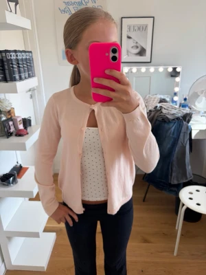 Ljusrosa kofta från H&M - Ljusrosa kofta från H&M med rundhalsringning, aldrig använd. Tunn i materialet och knäpps med knappar där fram.