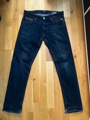 Replay Grover - Snygga mörkblå jeans från Replay med klassisk femficksdesign och raka ben. Jeansen har kontrastsömmar och en patch med Replay-logga bak i midjan. Perfekta för en avslappnad och trendig stil.