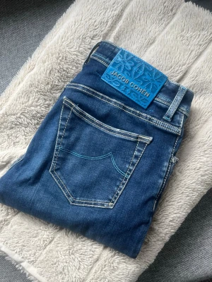 Jacob Cohen - Säljer ett par fina Jacob Cohen-jeans med en ovanlig patch. Jeansen är sparsamt använda och är ett riktigt fint plagg att ha i garderoben. De har lagts upp något och passar ungefär storlek 30/31, beroende på längd. Mycket snygga med en lyxig patch.