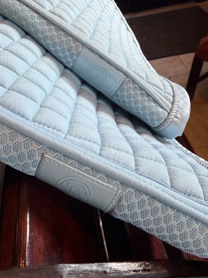 Ljusblått schabrak med quiltat mönster Eskadron - Säljer ett ljusblått schabrak med quiltat rutmönster och detaljer i mesh längs kanterna. Schabraket har en stilren design och är tillverkat i ett mjukt, vadderat material som ger bra komfort till hästen. Perfekt för dig som vill ha en snygg och funktionell utrustning till ridningen. Stropparna är avklippta. Säljes tvättat men med en del hår kvar samt några fläckar som syns på bild.